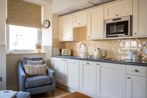 a kitchen with white cabinets and a chair and a microwave at Art House Apartments in Inverness