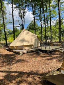 a tan tent with a table and a bench at Naturglamping in Kristianstad