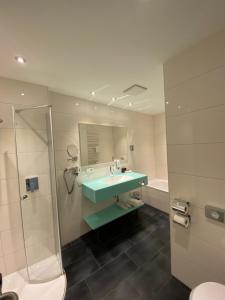 ein Badezimmer mit Waschbecken und Dusche in der Unterkunft Hotel Krone OHG in Gerlingen + 37 Fotos