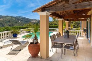un patio con mesa, sillas y piscina en Villa -Vue panoramique splendide -Piscine privée en Auribeau-sur-Siagne