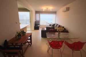 a living room with a glass table and red chairs at Fig Tree Bay Apartments in Protaras