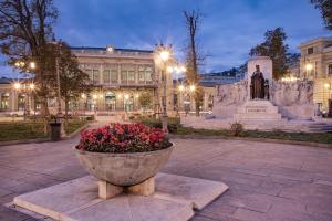 un grande edificio con una statua e dei fiori di fronte di Casanova Trieste Centrale a Trieste