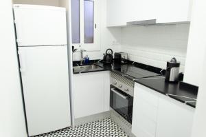 Apartamento NUEVO con encanto en SAGRADA FAMILIA في برشلونة: مطبخ أبيض مع حوض وثلاجة