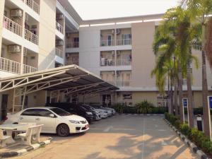 un parking avec des voitures garées devant un bâtiment dans l'établissement Baanbudsarin Apartment, à Singburi