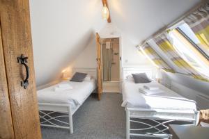Duas camas num pequeno quarto com uma janela em The Coal House em Kidwelly