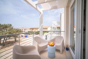 a balcony with white chairs and a view of the ocean at MERMAID'S HOUSE in Isola Rossa