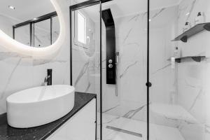 a white bathroom with a sink and a shower at Diogenis Seaside Suite in Rethymno Town +29 photos