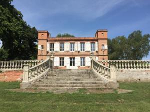 Saint-LysにあるChâteau Ratouの大きなレンガ造りの建物で、その前に階段があります。