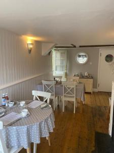 a dining room with tables and chairs and a kitchen at Ship Stores Guest House in Clare