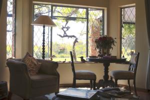 a living room with a table and chairs and windows at Gerald's Gift Guest House in Addo