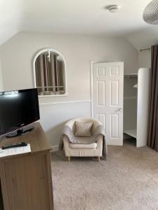 a living room with a tv and a chair and a door at Ship Stores Guest House in Clare