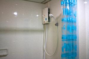 um chuveiro na casa de banho com uma cortina de chuveiro azul em Baanbudsarin Apartment em Sing Buri