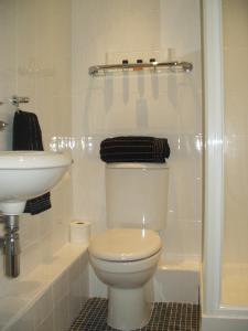 a white bathroom with a toilet and a sink at Ship Stores Guest House in Clare