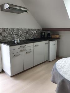 a kitchen with white cabinets and a black counter top at Avocette in Yvrench