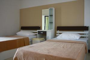 a bedroom with two beds and a mirror at Baanbudsarin Apartment in Sing Buri