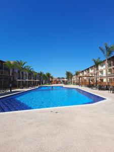 a large swimming pool in a resort with palm trees at Resort Ondas Praia in Porto Seguro