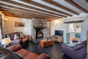 a living room with leather furniture and a stone fireplace at Bryntowy in Kidwelly