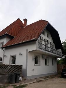 a white house with a red roof and a balcony at St. Kristóf Vendégház in Abádszalók