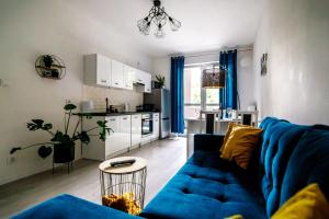 a living room with a blue couch and a kitchen at Apartament WHITE in Iława
