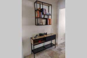 a room with a shelf and a table with books at La maison de Marie, maison de ville 4 personnes, option chambre patio 2 pers supp in Aigues-Mortes