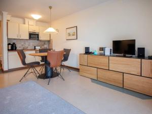 ein Wohnzimmer mit einem Tisch und einem TV sowie eine Küche in der Unterkunft Strandvillen Binz - 1-Raum-Ferienwohnung mit Meerblick und Balkon SV-763 in Binz