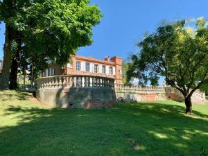 un gran edificio de ladrillo con un árbol en un campo en Château Ratou en Saint-Lys