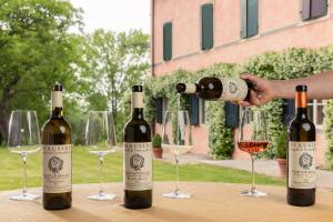three bottles of wine on a table with wine glasses at Tenuta Perusini in Corno di Rosazzo