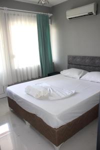 a bedroom with a large bed with white sheets and a window at Alpat Homes in Kemer