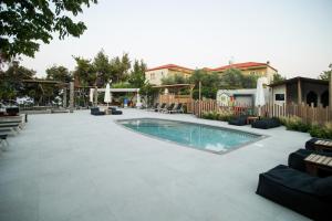 a swimming pool in a patio with chairs and a fence at Nostos Hotel in Afitos