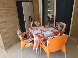 uma mesa de jantar com cadeiras laranja e uma mesa com uma toalha de mesa em Apartamento 1ª línea de playa em Oropesa del Mar