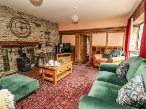 a living room with green furniture and a stone wall at Pant Y Rhedyn in Llandrindod Wells