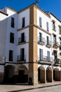 ein weißes Gebäude mit einem Torbogen davor in der Unterkunft Apartamentos El Patio Plaza Mayor Cáceres in Cáceres