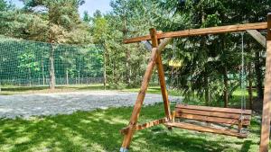 a wooden swing in a park with green grass at Polana Świerkowa in Okuninka