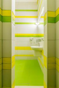 a bathroom with green and yellow striped walls and a sink at Vorobey Hostel in Kyiv