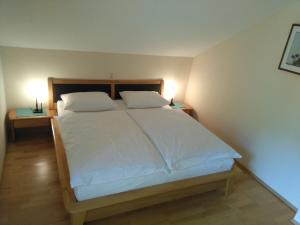 een bed met witte lakens en kussens in een slaapkamer bij Appartement Enzi in Sekirn