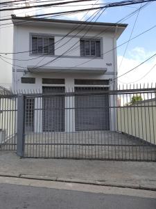 a white house with two garage doors and a fence at Pousada Monte Alegre in Sao Paulo