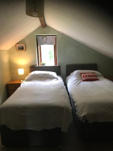 two beds in a small room with a window at Maes yr Helmau Cottages in Dolgellau