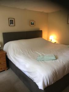 a large white bed with a blue towel on it at Maes yr Helmau Cottages in Dolgellau