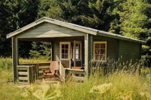 a small green house with a chair in a field at Nature retreat in a beautiful off-grid cabin in Rouge