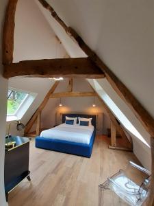 ein Schlafzimmer mit einem blauen Bett im Dachgeschoss in der Unterkunft Château de la Bribourdière in Putot-en-Auge