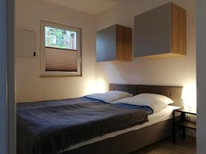 una camera da letto con un letto con una coperta blu e una finestra di Domek nad jeziorem a Kamienica Królewska