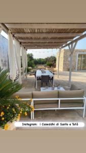 d'une terrasse avec une table et des chaises sous une pergola. dans l'établissement i Caseddhi di Santo e Totò, à Torre Suda