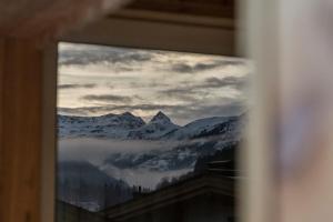 a view of a snowy mountain through a window at FRAU GANS - pure mountain apartments in Saalbach Hinterglemm