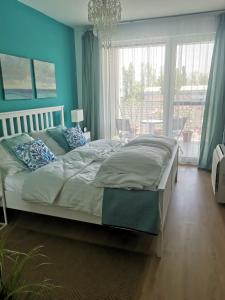 a bedroom with a bed with blue walls and a window at Vízpart Hullám Apartman in Balatonlelle