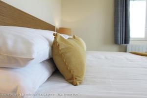 uma cama com almofadas brancas e uma cabeceira castanha em The Old Quay House em Hayle