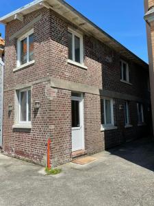 een bakstenen gebouw met een witte deur en ramen bij Chambre d'hôtes des pins in Cayeux-sur-Mer
