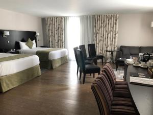 um quarto de hotel com duas camas e uma sala de estar em Auberge des Gallant em Rigaud