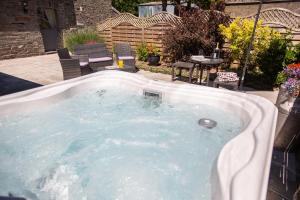 a hot tub in a backyard with a table and chairs at The Coal House in Kidwelly