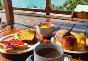 una mesa con dos platos de comida y una taza de café en Na praia - Araça 305 Super luxo - Frente mar, en Natal