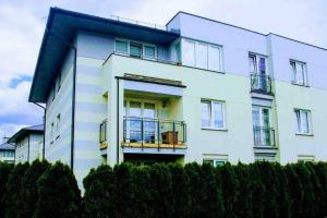een wit appartementencomplex met een balkon en struiken bij Piękne mieszkanie 20 min od centrum Warszawy in Parzniew